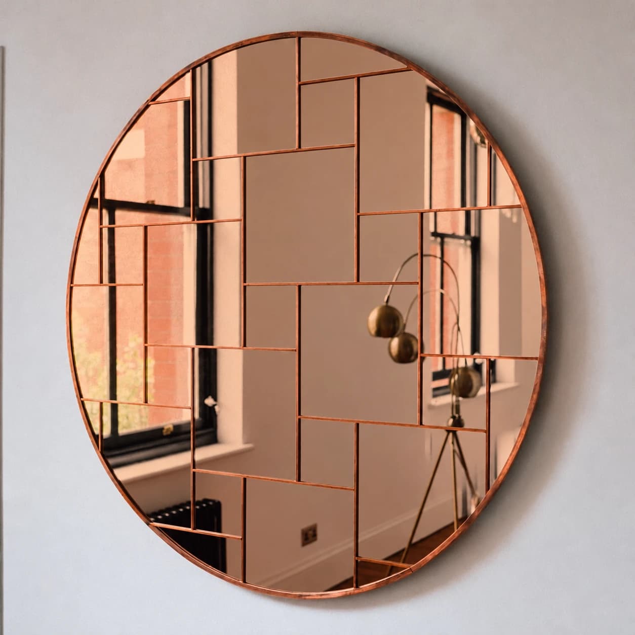 Rotation Mirror in Copper Tone — a round mirror of copper-toned glass facets set in solid copper, reflecting a sash window